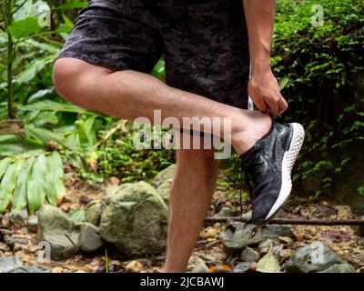 La Estrella, Antioquia, Colombia - February 13 2022: Man Taking out his Shoes in the Dirty Road of the Forest Stock Photo