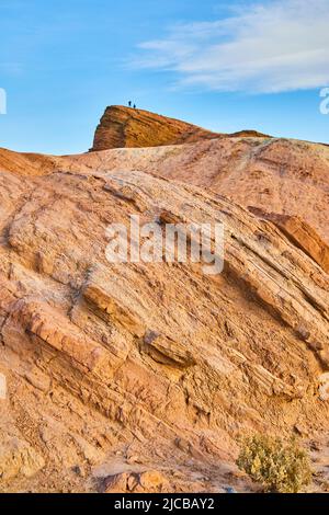 Lone figures at top of large red rock formations in desert Stock Photo