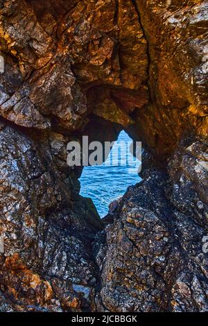 Ocean view seen through tunnel of sharp rocks Stock Photo