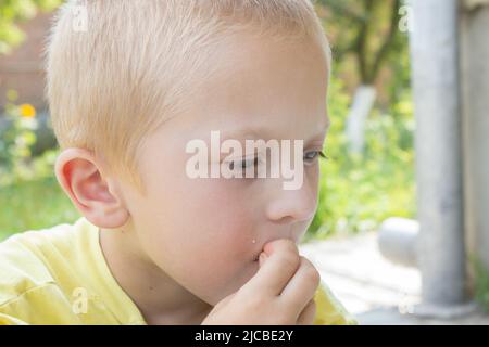 Portrait blond boy who eats with his hands Stock Photo