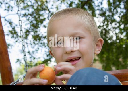 portrait of a toothless boy sitting on a bench Stock Photo