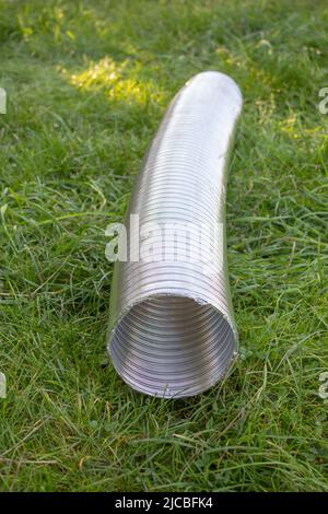 Corrugated exhaust pipe lying on the grass Stock Photo