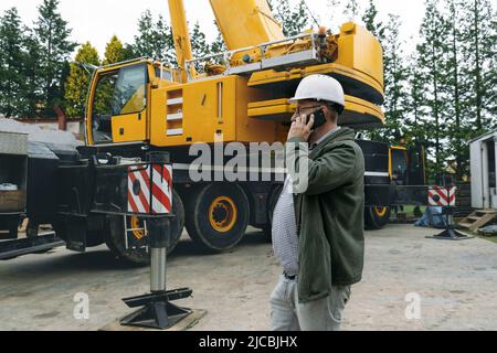 Foreman talking by phone on construction site. architect discussing project using smart phone, construction engineers planning building. Communication Stock Photo