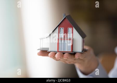 Closeup female hand holding on palm small cottage house model Stock Photo