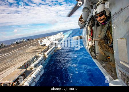 Philippine Sea. 3rd June, 2022. Naval Air Crewman (Helicopter) 2nd Class John Kainoa IV, from Waikoloa, Hawaii, prepares to land a helicopter assigned to the Golden Falcons of Helicopter Sea Combat Squadron (HSC) 12 aboard the U.S. Navy's only forward-deployed aircraft carrier USS Ronald Reagan (CVN 76), during Carrier Strike Group Exercise 2022. Carrier Strike Group Exercise is a bilateral exercise between the U.S. Navy and Republic of Korea Navy. This exercise allows our navies to refine operations and engagement to strengthen future cooperation while supporting the alliance that remains v Stock Photo