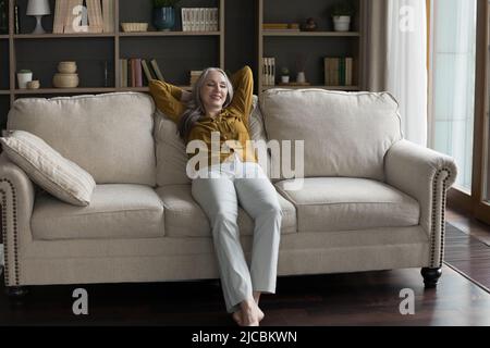 In warm living room beautiful middle-aged woman relaxing on sofa Stock Photo