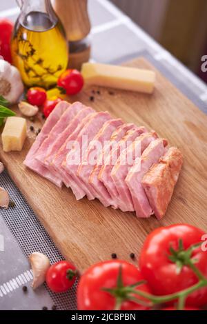 sliced pancetta ham bacon on wooden cutting board at domestic kitchen Stock Photo
