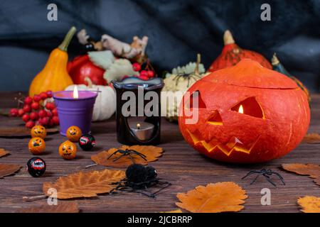 Halloween pumpkins on a wooden dark table with spiders, candles, pumpkins, leaves. Halloween concept. Stock Photo