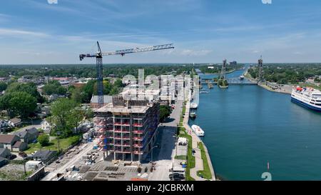 A new condo building under construction with a large crane on site is seen in an urban city located next to a canal. Stock Photo