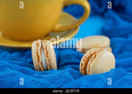 yellow cup of coffee and macaroons on blue background Stock Photo