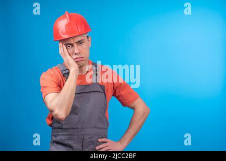 Weary male contractor in uniform touching face Stock Photo