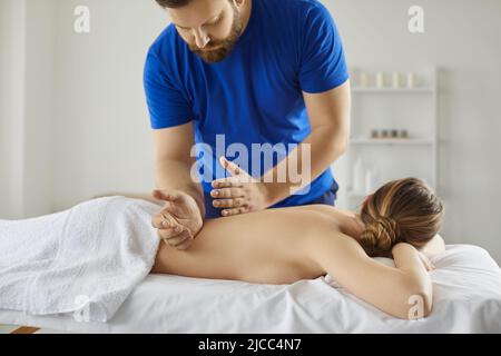 A man is a chiropractor doing a massage to a woman in the neck and trapezius  muscles in his office Stock Photo - Alamy