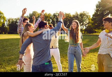 Group of happy young people have fun together while walking in park on warm summer evening.