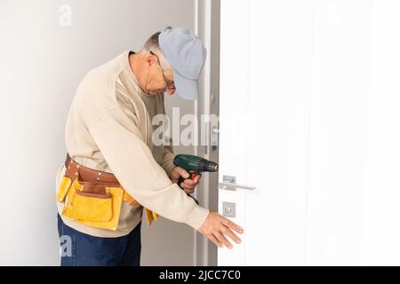 Worker man installs plastic windows white lock and seal adjustment. Stock Photo