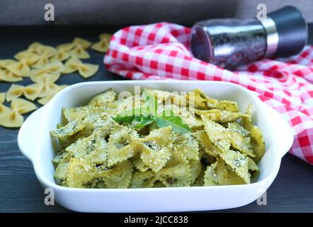A Bowl of Delectable Homemade Farfalle Pasta with Pesto Sauce on Kitchen Table Stock Photo