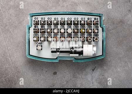 A set of metal power bits in a box on a gray background, for repair and maintenance Stock Photo
