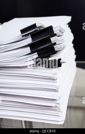 A stack of office papers, some of which are fastened with black binders Stock Photo
