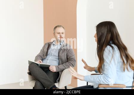 A male psychologist listens attentively to a female patient. Stock Photo