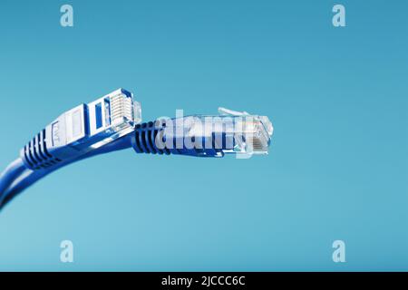 Blue Ethernet Cable Connectors Patch cord cord close-up isolated on a blue background with free space Stock Photo