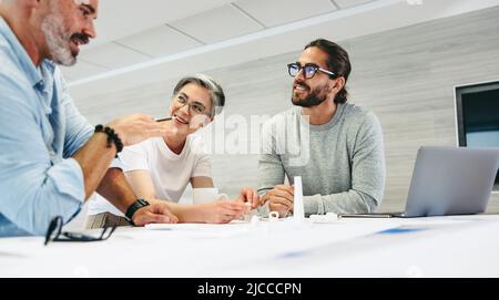 Happy design professionals having a discussion while working on a wind turbine project. Group of innovative businesspeople sharing creative ideas in a Stock Photo