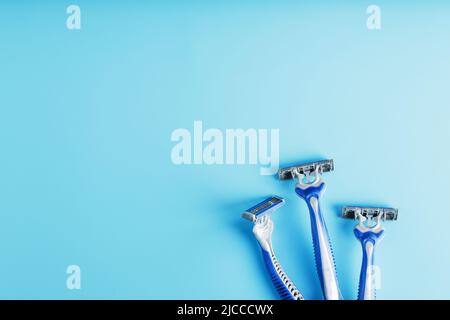 Three shaving machines on a blue background with free space, top view Stock Photo