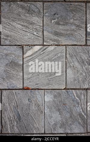 Typical and common square marble tiles serving as pavers on a fancy sidewalk. Stock Photo
