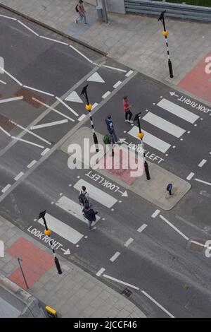 High-angle view of pedestrians crossing a black-and-white zebra crossing in London, capturing the rhythm, movement and distinctive visual geometry. Stock Photo