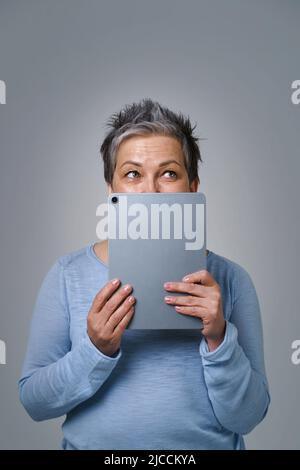 Scared mature woman on light blue background Stock Photo - Alamy
