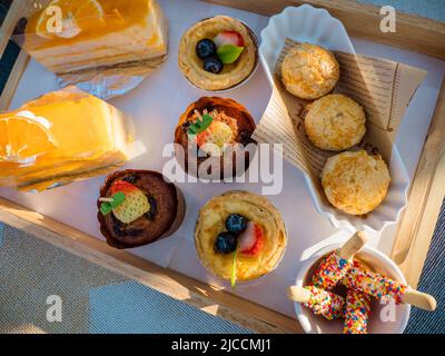 A variety of cakes and sweets in beautiful wooden trays. Sunday picnic in the garden with nature. Stock Photo
