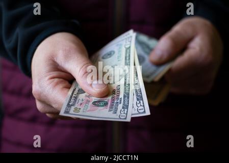 Two fifty dollar bills in white male hand closeup Stock Photo