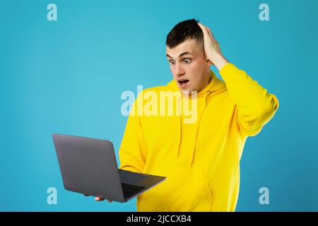 Confused Guy Using Laptop Scratching Head Having Problem, Blue Background Stock Photo