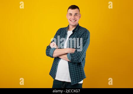 Cheerful Young Man Standing Crossing Hands Posing Over Blue Background Stock Photo