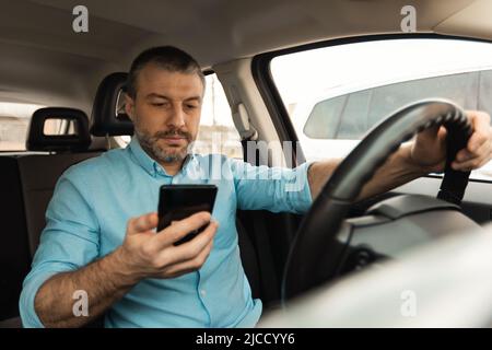 Male Driver Using Smartphone For Navigation Driving New Car Stock Photo