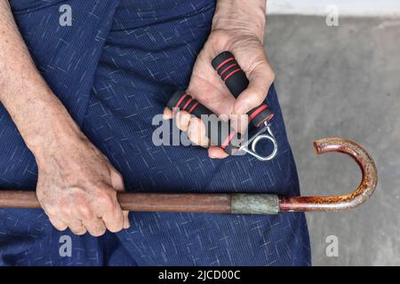 Southeast asian, Myanmar old man gripping hand exercise gripper. Stock Photo