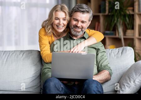 Portrait Of Happy Middle Aged Couple Using Laptop At Home Stock Photo