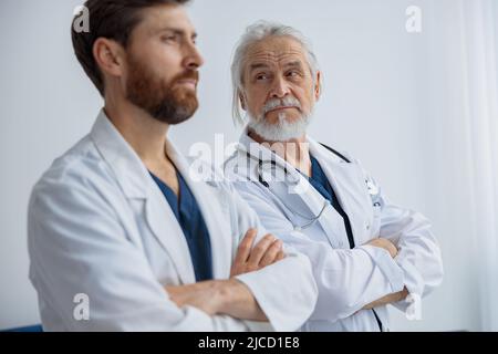 Two professional doctors in uniform standing in hospital with crossing arms Stock Photo