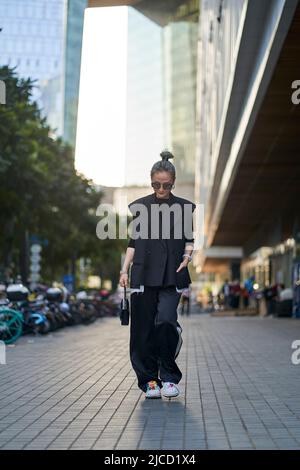 fashionable mid adult asian woman walking on street Stock Photo