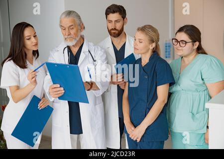 Doctor giving lecture to interns in hospital discussing patient diagnosis Stock Photo