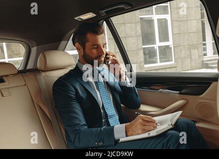 Handsome bearded head in formal wear working during the travel by a car Stock Photo