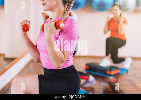 Group of women doing lunges with dumbbells in their hands Stock Photo