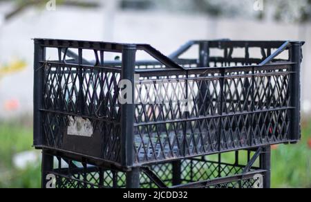 Plastic empty black boxes stacked together for plants or harvest. On a sunny day in early spring. Gardening concept. Household crop collection and sto Stock Photo