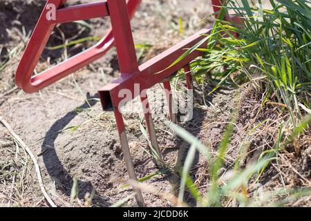 Red shovel in the form of a fork in the garden. Miracle shovel, handy tool. Manual cultivator. The cultivator is an effective tool for tillage. Bed lo Stock Photo