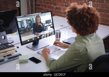 Biracial businessman discussing strategies with female coworker through desktop pc in office Stock Photo