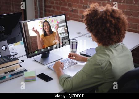 Biracial businessman working online with businesswoman through video call on desktop pc in office Stock Photo