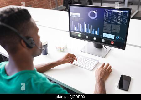 High angle view of african american businessman analyzing graphs over computer on desk in office Stock Photo