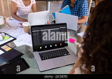 Caucasian businesswoman working over laptop while sitting with female colleagues in office Stock Photo
