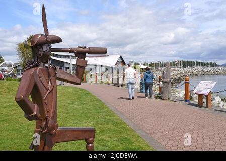 A view of a sculpture of a pirate with a telescope and the harbour and marina in Sidney, British Columbia on Vancouver Island, Canada. Stock Photo