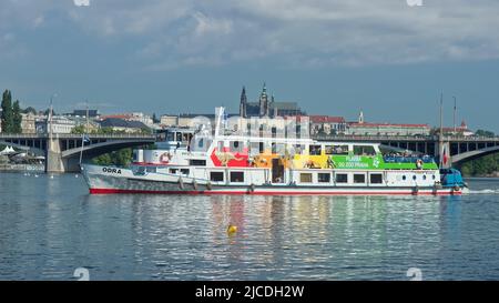 PRAGUE - June 11: Cruise boat Odra leaves the pier and sets sail for the zoo on June 11, 2022 on Vltava river, Czech Republic. Prague Castle in backgr Stock Photo