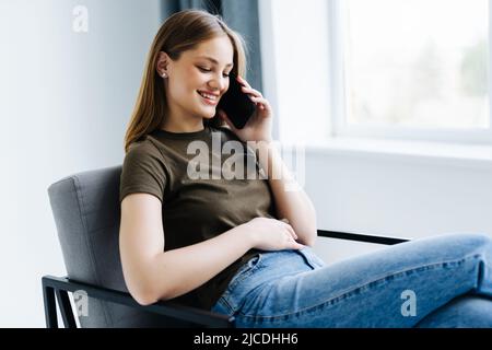Happy young woman talking on the phone at home Stock Photo