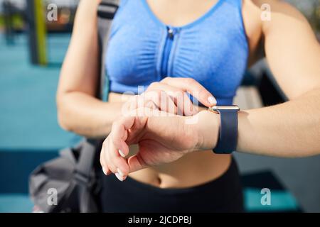 Close-up of unrecognizable female athlete standing outdoors and using fitness app on smartwatch to get fit Stock Photo